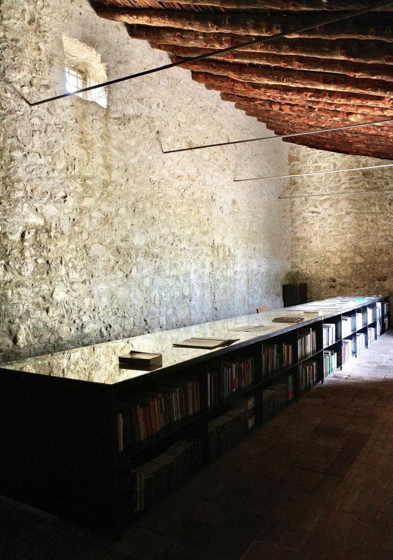 sala con muro inpietra e espositore libri